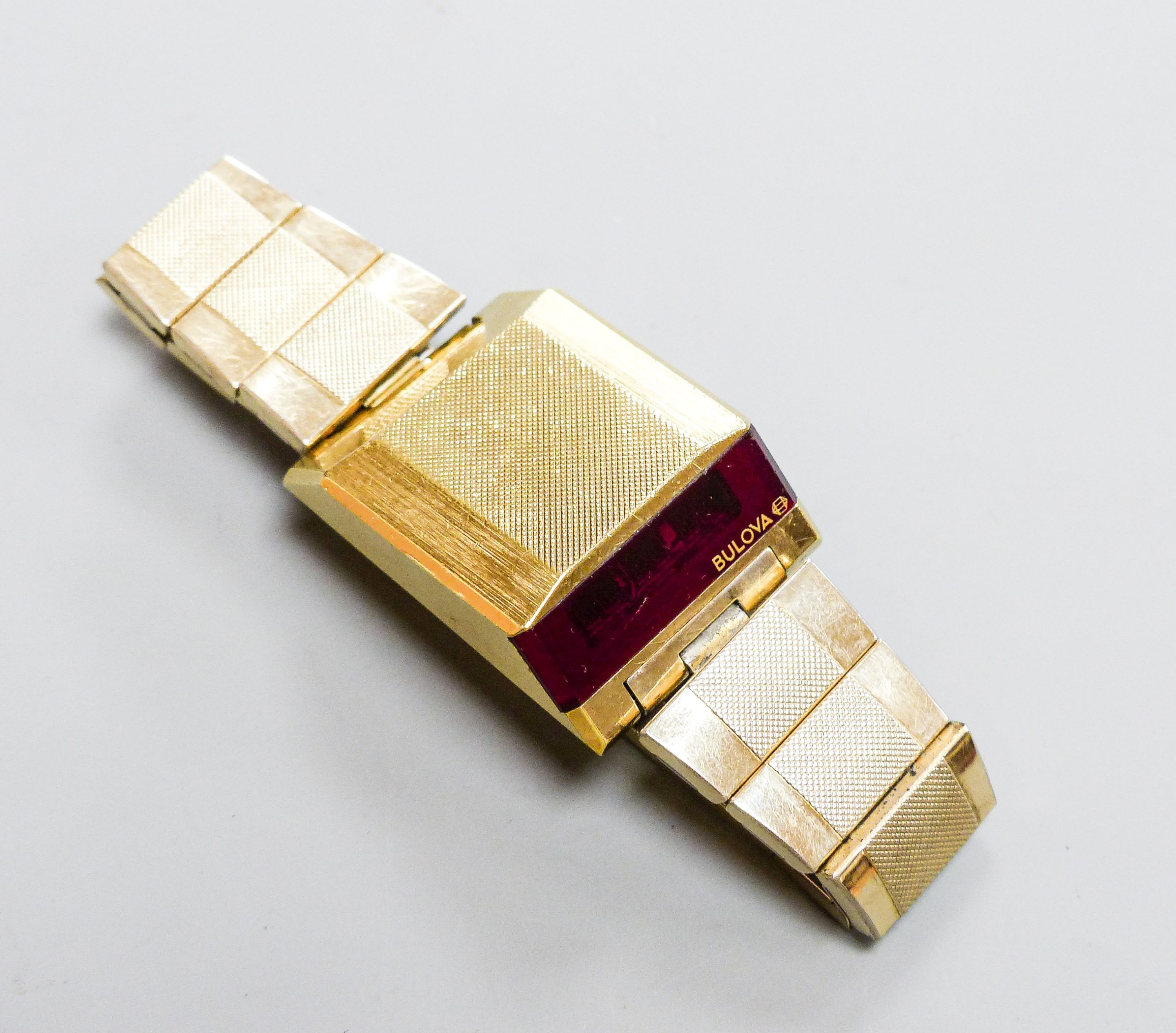 A gentleman's steel and gilt base metal Bulova digital wrist watch, on Bulova bracelet, case diameter 30mm (a.f.).